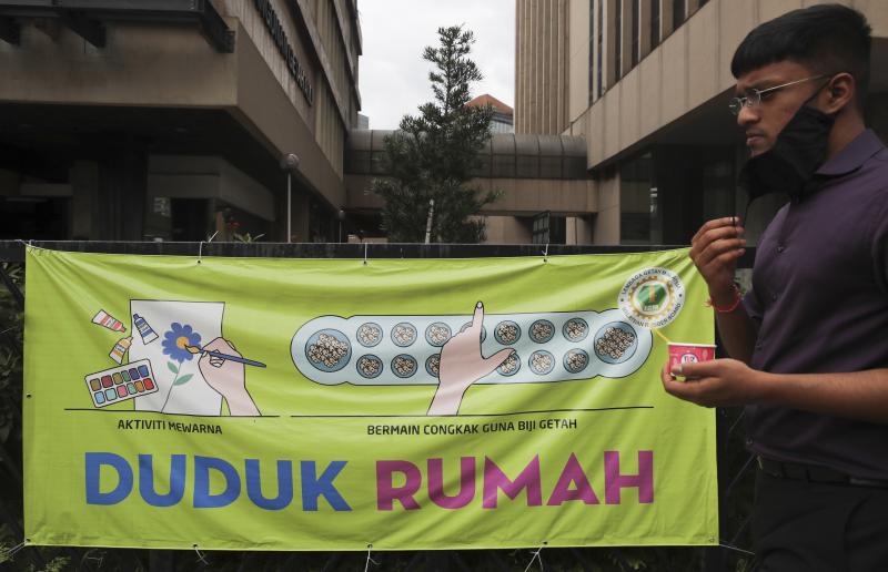 21012021 A man wearing a face mask walks past a banner reading 'Stay home' in Kuala Lumpur .jpg