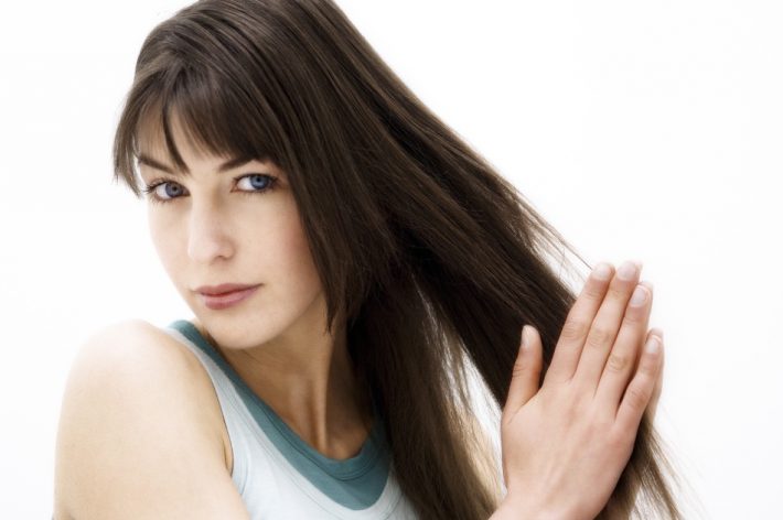 Portrait of a young woman rubbing her hair (studio)